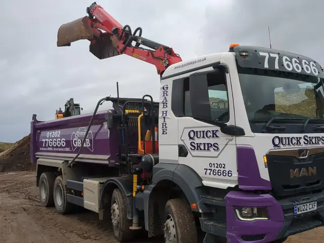 Grab lorry with arm extended loading material on site